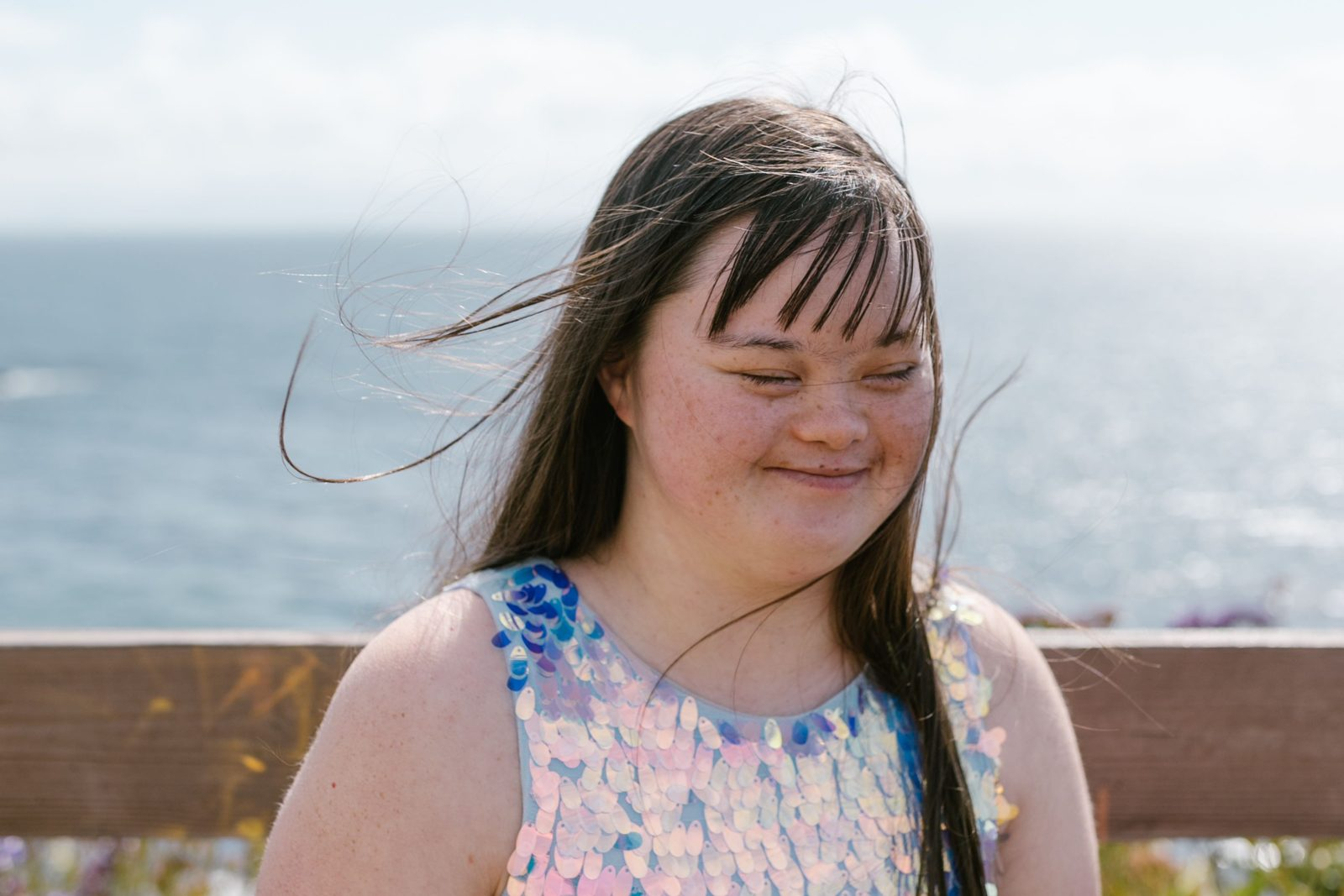 A smiling young woman enjoying a sunny day by the sea