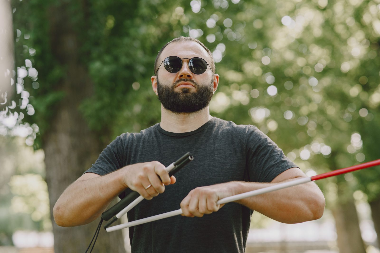 A confident man using a white cane while walking outdoors